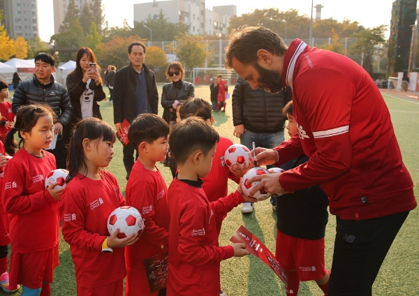 리버풀 축구교실에 참가한 축구 꿈나무들이 리버풀FC 레전드인 패트릭 베르게르 선수(맨 우측)에게 사인을 받고 있다. (사진=SC제일은행)